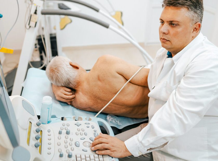 Male doctor examining a patient's heart by using an ultrasound equipment